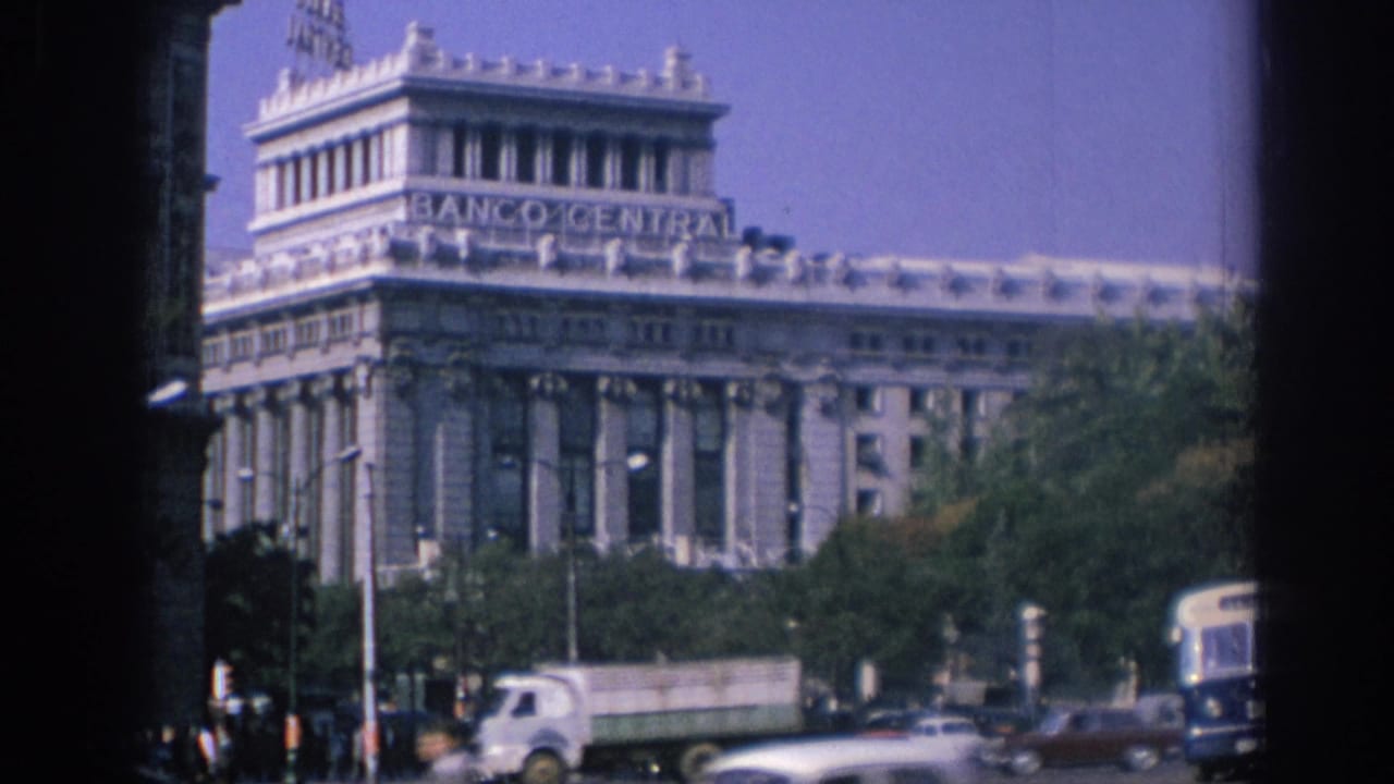 1966 Spain city traffic with a truck, cars, trees, and the Banco Central facade visible beyond the street.