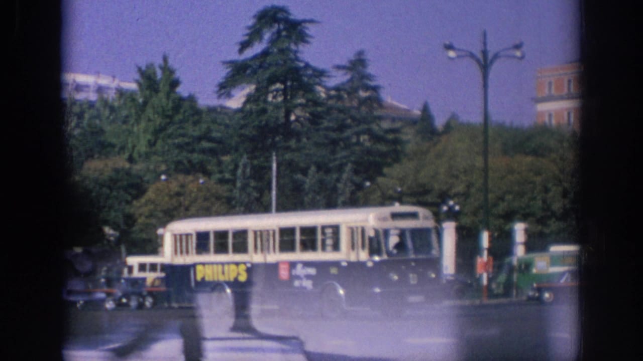 1966 Spain street view with a Philips-branded bus, classic cars, trees, lampposts, and partial film gate edges visible.