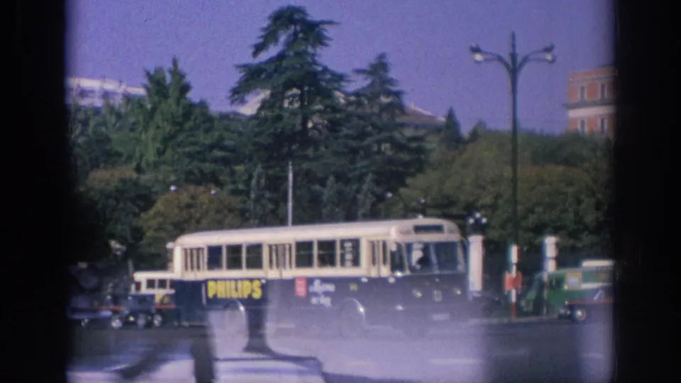 1966 Spain street view with a Philips-branded bus, classic cars, trees, lampposts, and partial film gate edges visible.