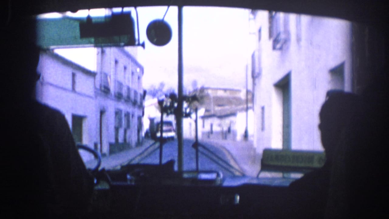 1966 Spain bus interior view looking through the windshield at white buildings along a narrow town street.