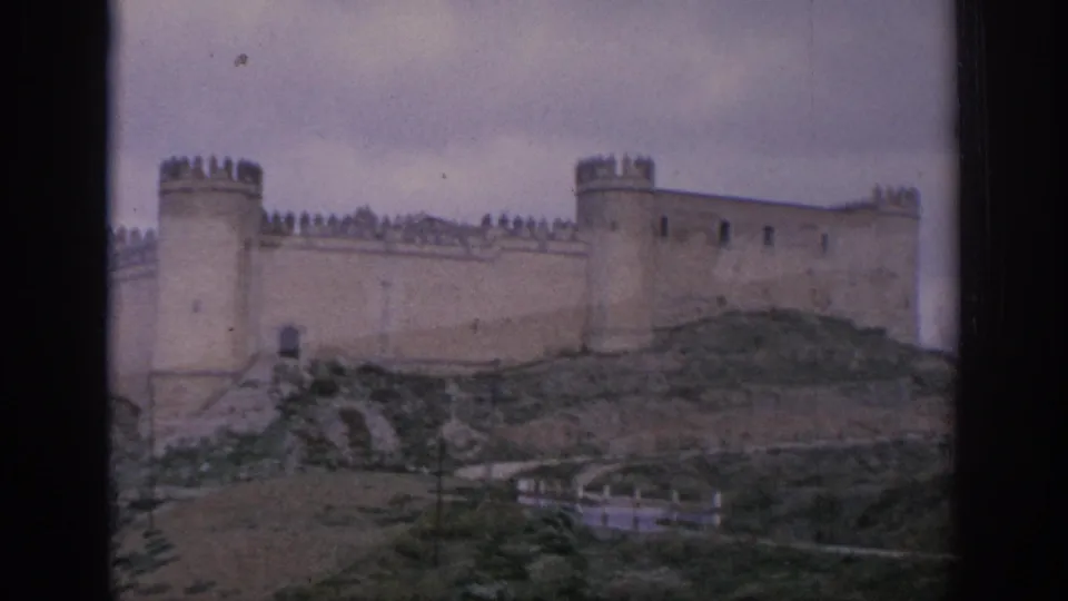 1966 Spain travel frame holding on a hilltop castle with battlements, round towers, grassy foreground, and visible 8mm border.