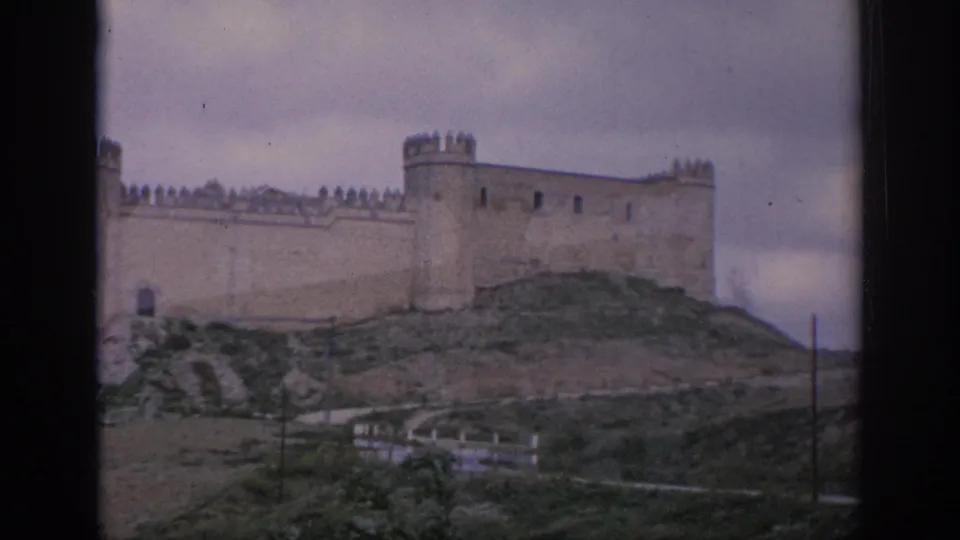 1966 Spain travel frame with castle towers, crenellated walls, hillside ground, and soft 8mm color.