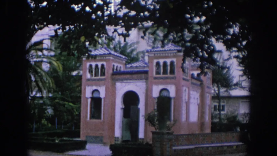 1966 Spain 8mm frame showing a small ornate structure with arched windows, tiled roof details, and surrounding foliage.