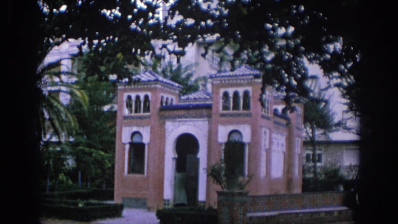 1966 Spain home-movie frame showing a small Moorish-style garden pavilion with arches, tiled roof details, trees, and a path.
