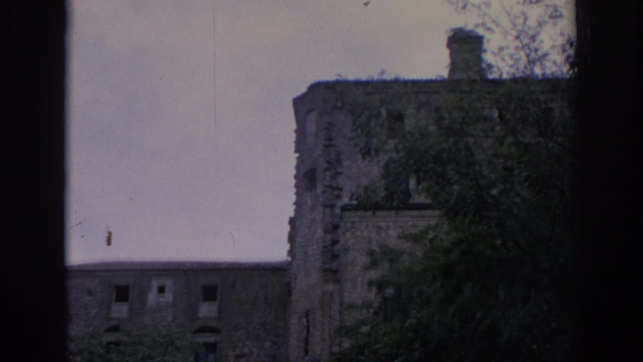 Rounded stone building section with trees and dark framing at the edge.