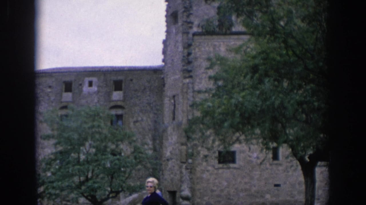 Stone building with trees in front and a person partly visible near the lower edge.