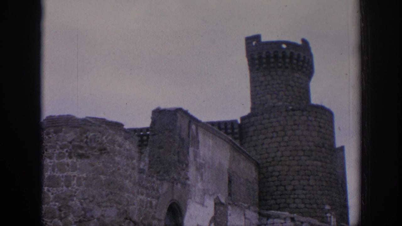 1966 Spain 8mm frame showing weathered stone ruins and a round crenellated tower beneath an overcast sky.