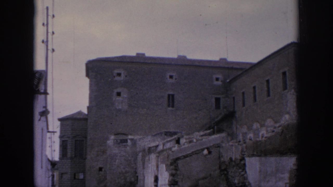 1966 Spain 8mm view of a plain historic building, broken walls, and a utility pole near the ruins.