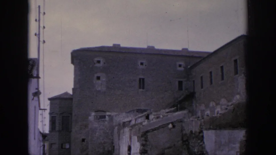 1966 Spain 8mm view of a plain historic building, broken walls, and a utility pole near the ruins.