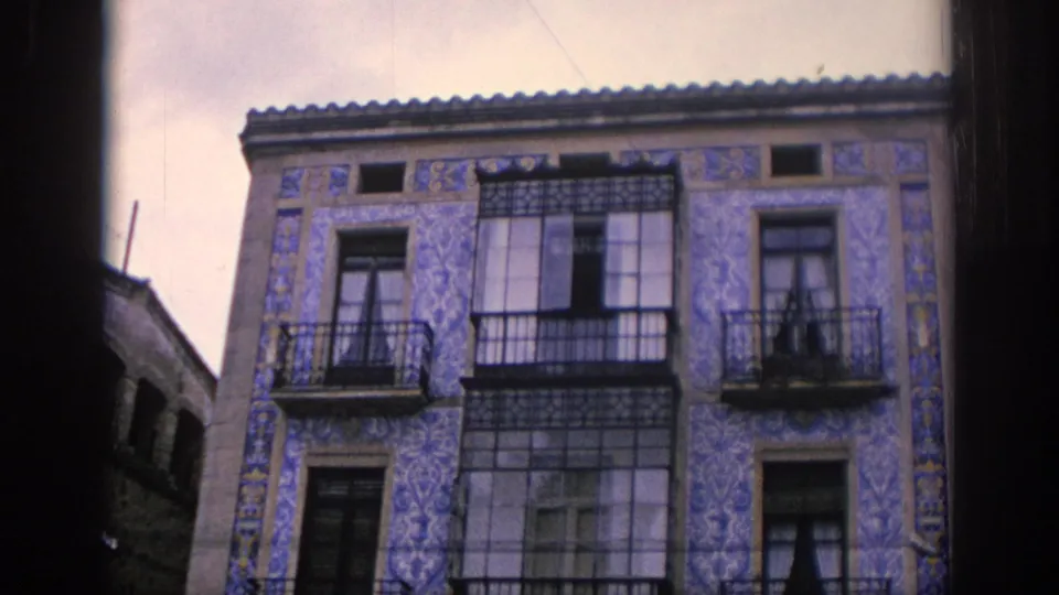 1966 Spain frame showing an ornate blue-and-white tiled residential facade with wrought-iron balconies and tall windows.