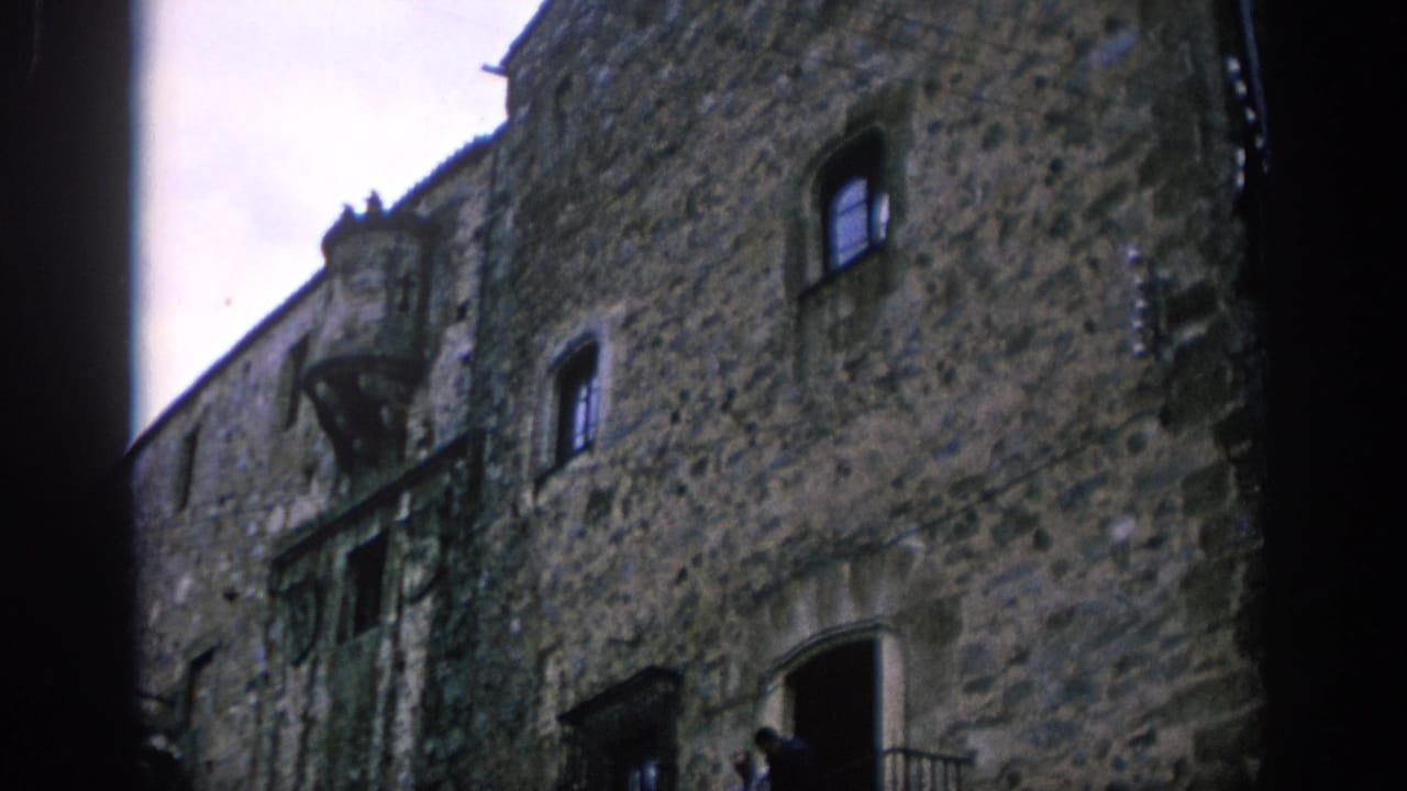 Stone building facade with arched doorway and two people briefly near the entrance.