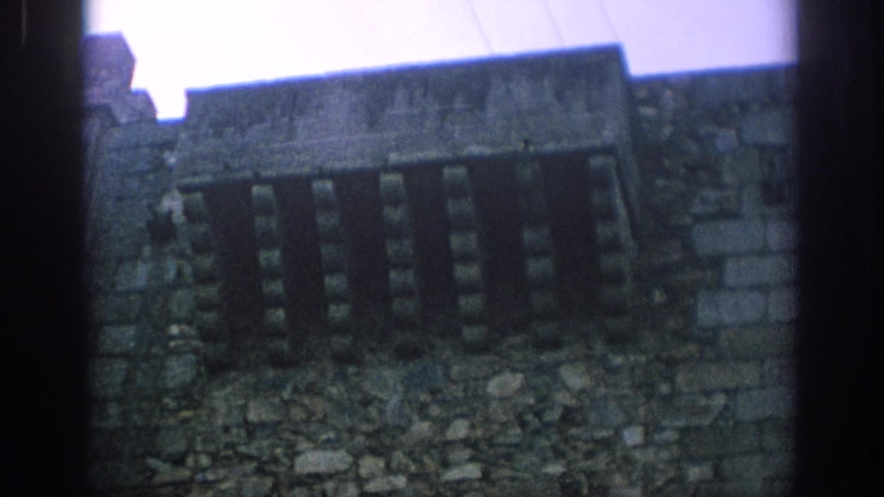 Weathered stone battlements and narrow windows seen from inside a castle area.