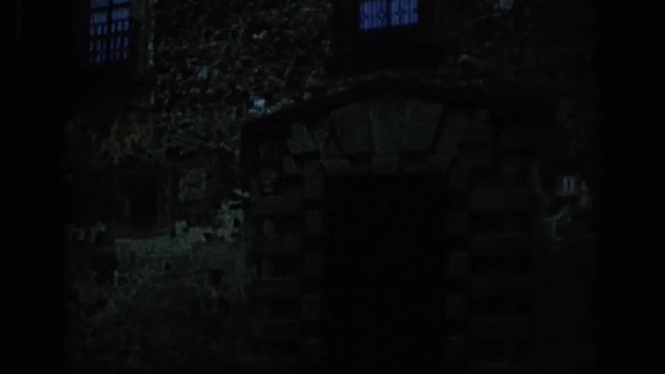 1966 Spain 8mm frame of a shadowed arched doorway, rough masonry, and barred windows within the castle grounds.