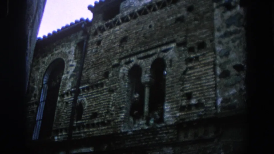 A 1966 Spain travel-film view of a stone-and-brick building facade with paired arched windows and deep shadows.