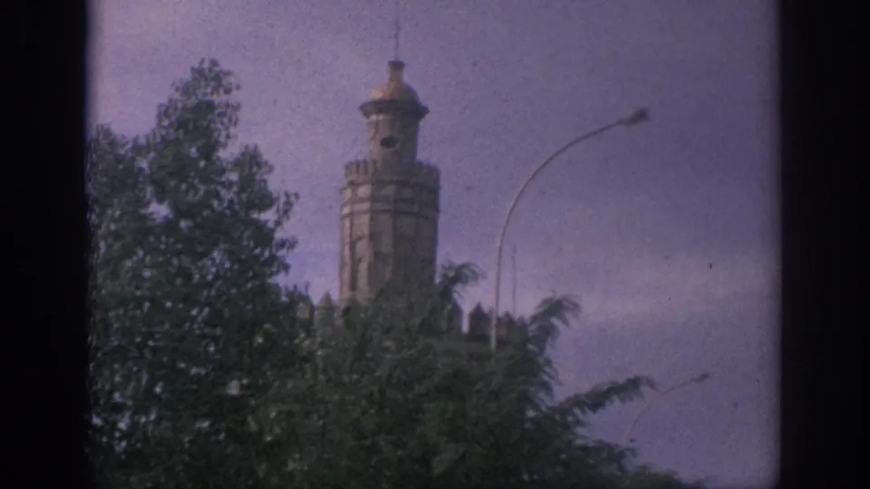 Daylight 1966 Spain frame showing a pale tower above green trees, with a curved streetlight against the sky.