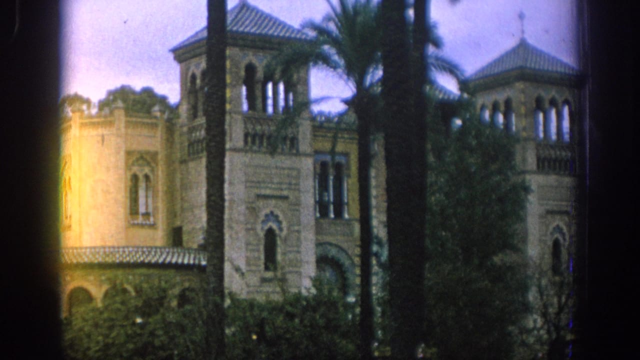 1966 Spain travel frame showing a Moorish-style facade with arched openings, palm trees, shrubs, and warm flare along the left side.