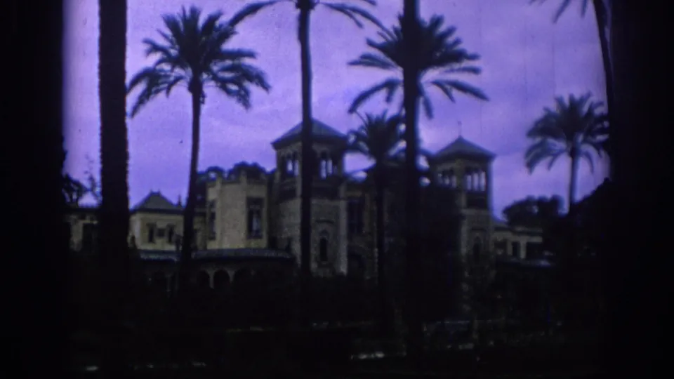 Palm-lined Spanish resort or garden building appears in a soft 8mm establishing shot from 1966.