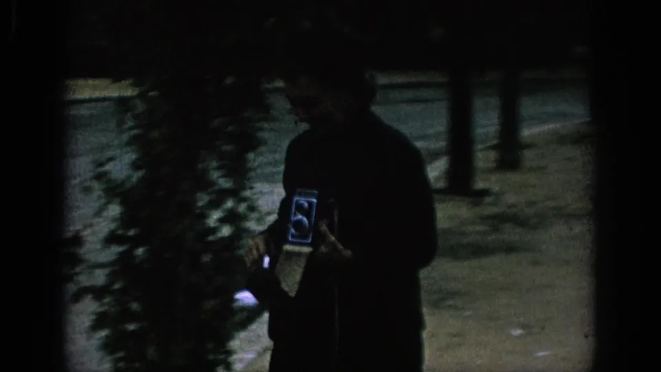 A silhouetted man holds a vintage twin-lens reflex camera in the same 1966 Spanish park or garden scene.