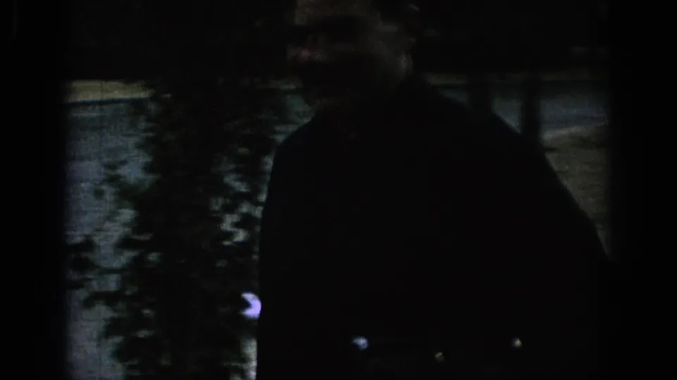 The home movie shows a dark silhouetted man moving through the 1966 Spanish garden, with a camera partly visible.