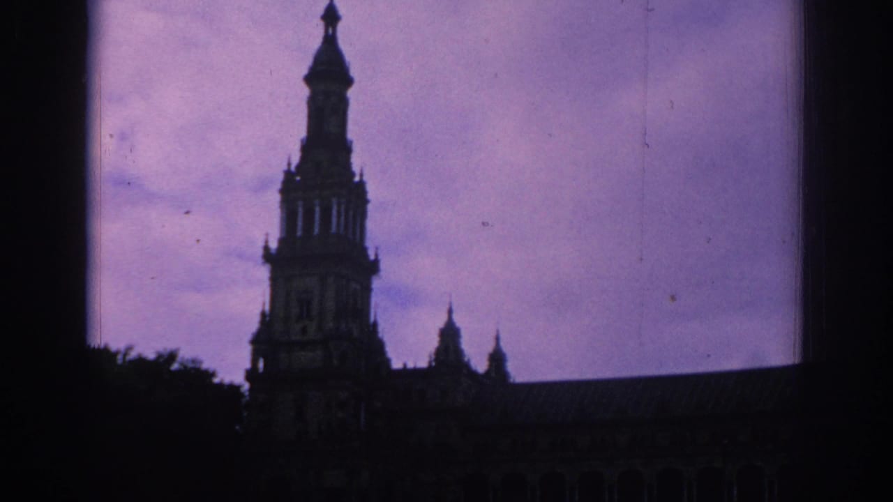 Dark silhouette of an ornate tower and roofline against a purple sky.