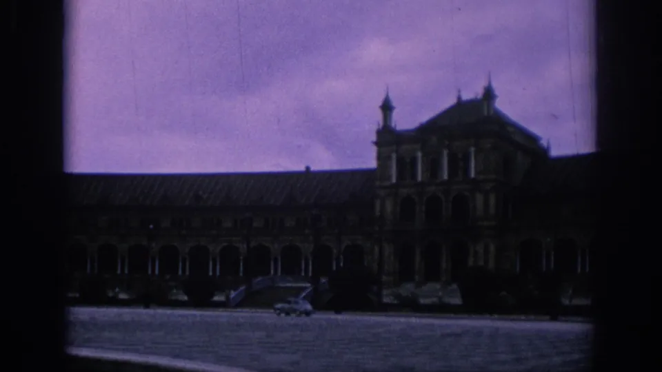 A wider 1966 Spain view shows a historic facade with arched openings and several parked cars beneath a purple-toned sky.