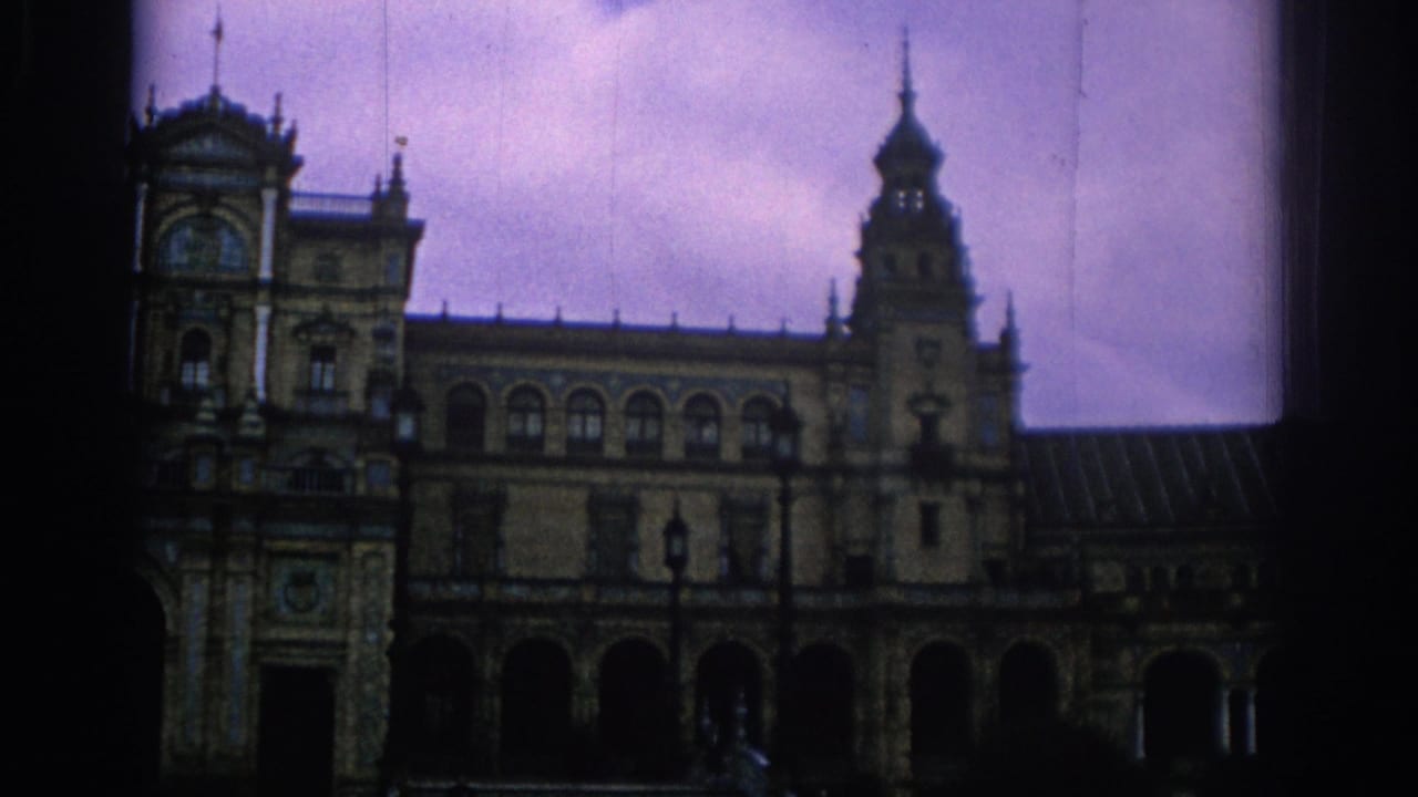 Ornate historic building facade with arches and towers under a purple cloudy sky.