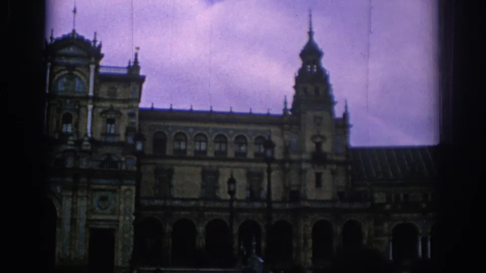1966 Spain home-movie frame showing an ornate historic facade with arched openings, towers, and dark 8mm frame edges.