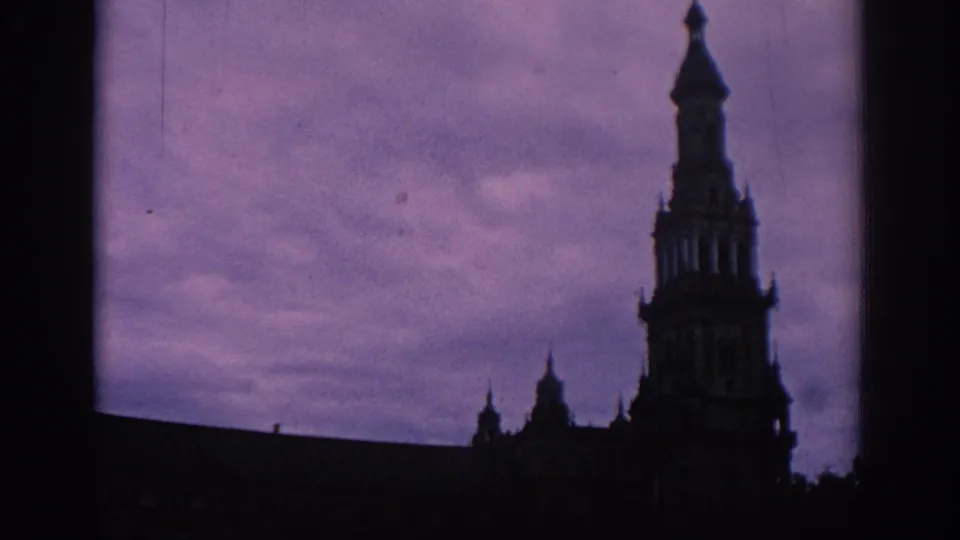 1966 Spain frame showing the silhouette of a decorative tower and roofline against a purple-tinted sky.