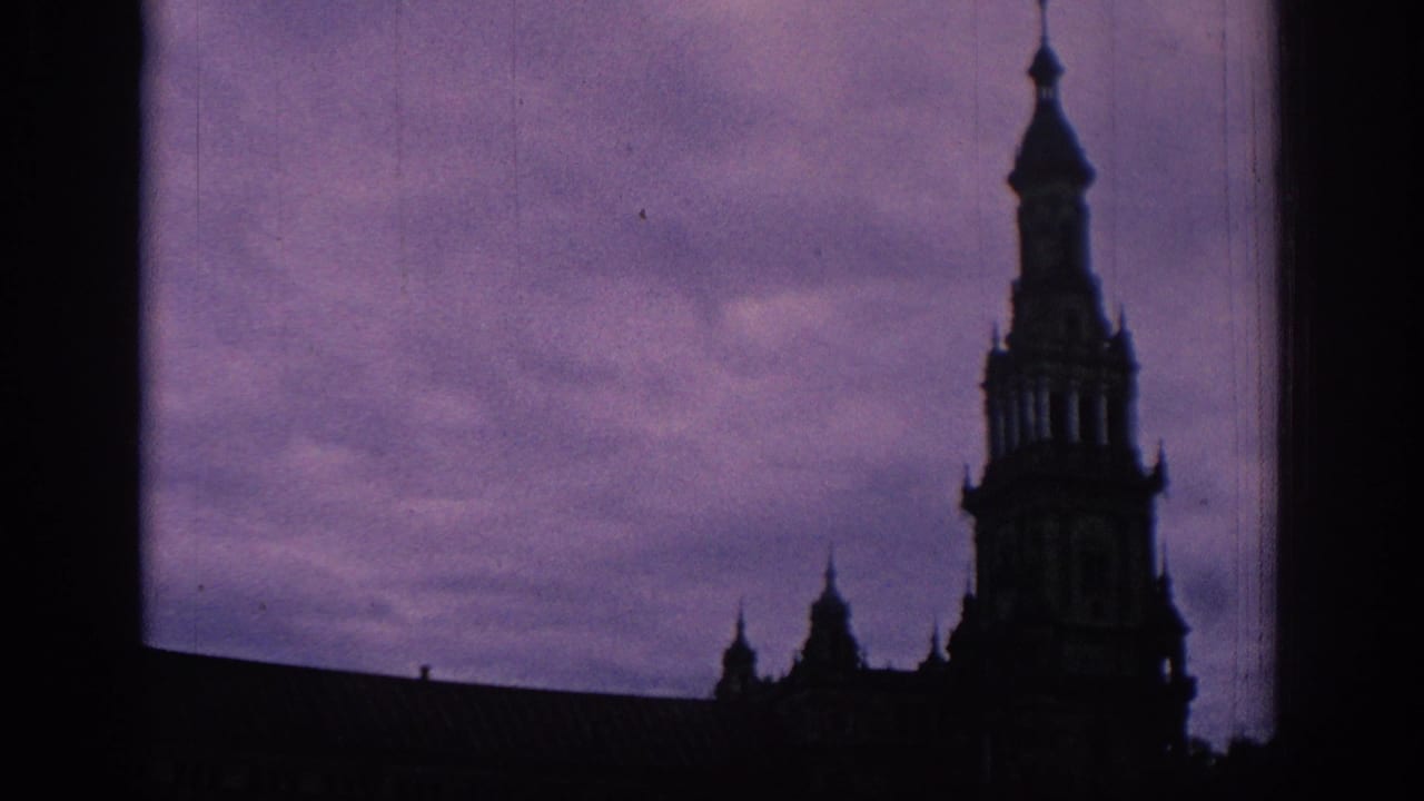 1966 Spain 8mm frame showing an ornate tower and roofline in silhouette beneath a violet twilight sky, with dark gate edges visible.
