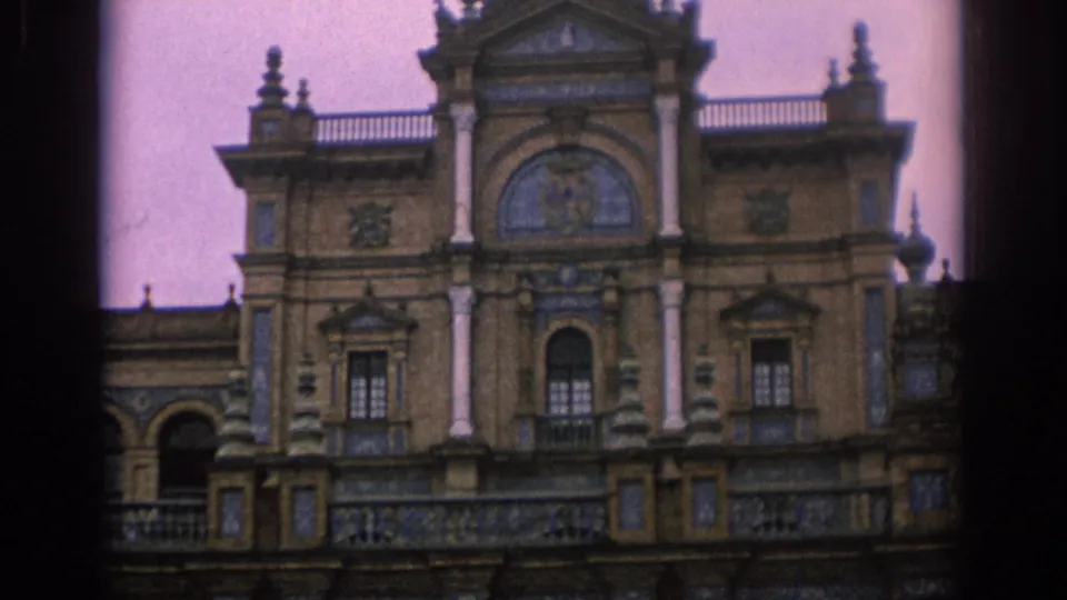 1966 Spain 8mm frame showing a closer ornate facade with columns, arched openings, balconies, and blue-toned tilework.