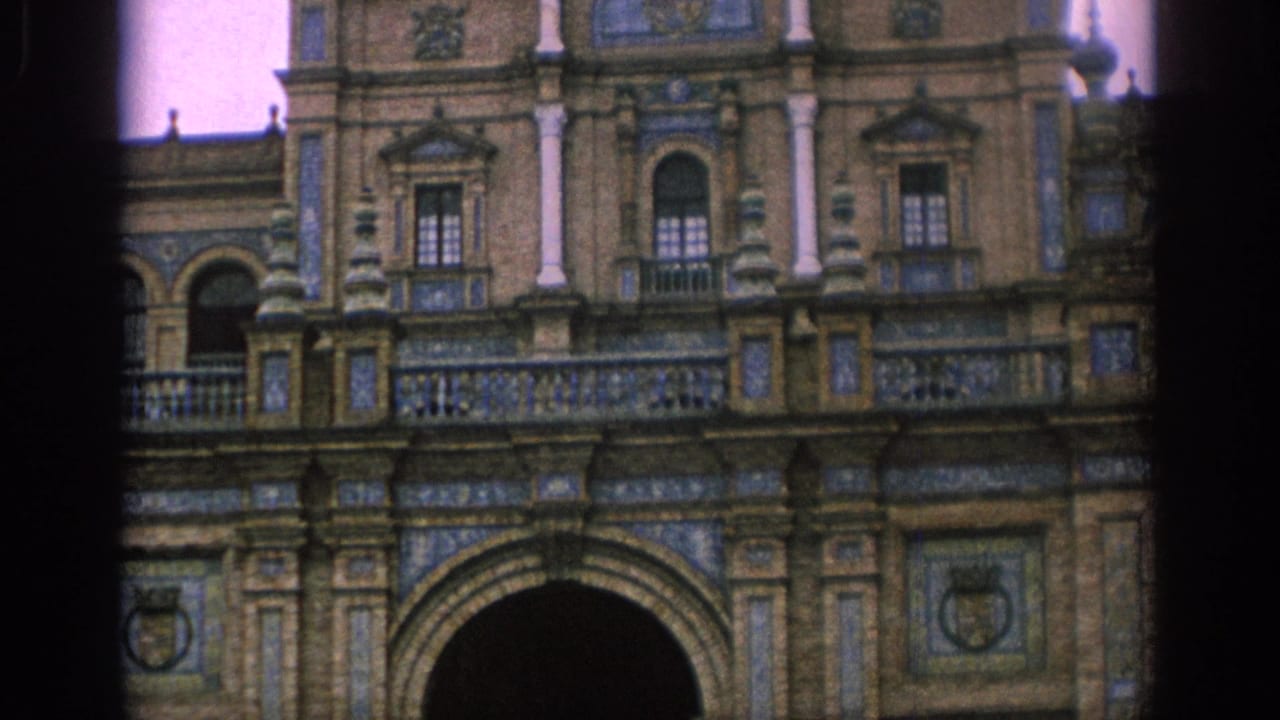 1966 Spain frame of a grand historic facade, showing decorative tilework, stone columns, balcony railings, and the top of a large central arch.