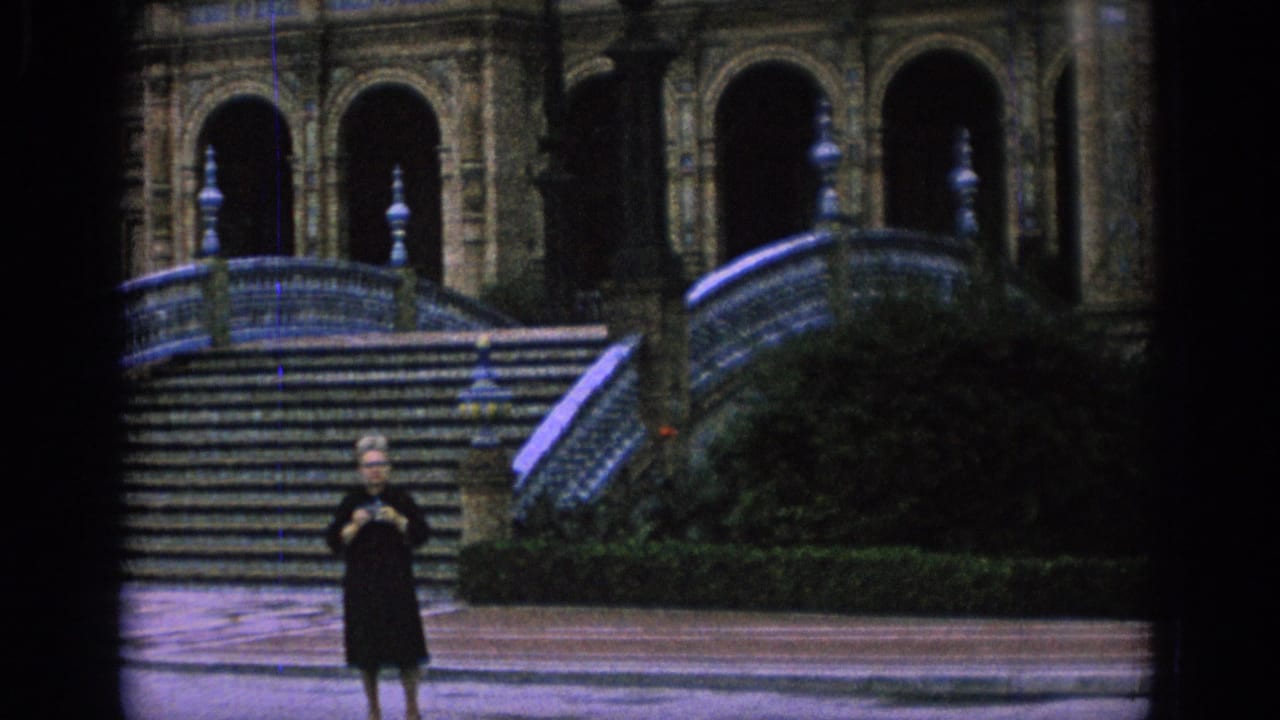 Woman in a black dress stands before tiled steps and arched architecture.