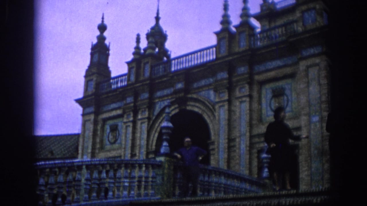 Wide 8mm view in Spain, 1966, showing two adults posing on a tiled balcony beneath arched architecture.