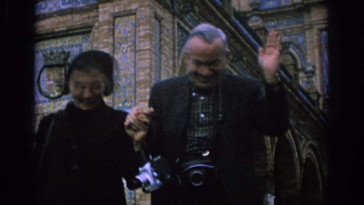 In Spain in 1966, a smiling couple walks near ornate tilework and stairs while the man waves toward the 8mm camera.