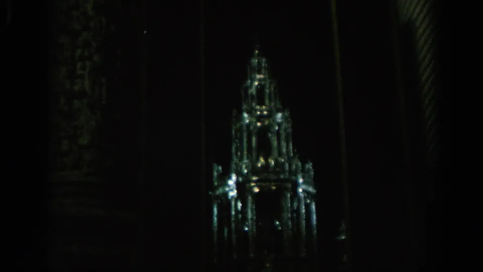 Dark 8mm interior view in Spain showing a glowing glass or crystal structure resembling a miniature castle or spire.