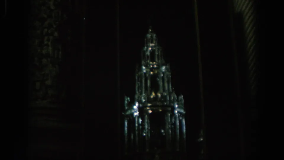 Final 8mm frame of the illuminated crystal-like castle or cathedral-spire display in a shadowed interior setting.