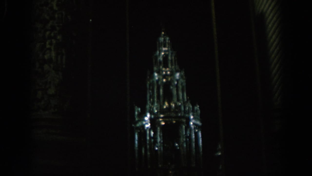 1966 Spain 8mm frame showing a historic tower illuminated at night, with most of the surrounding scene in deep shadow.
