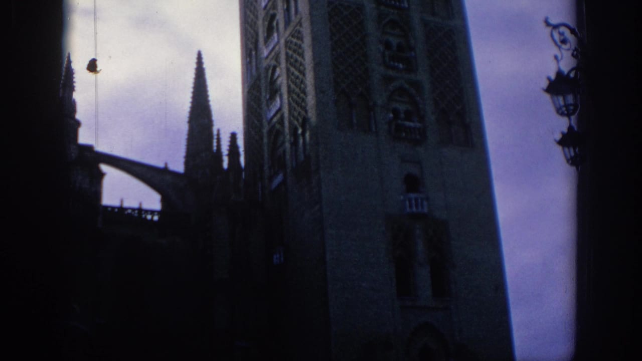 1966 Spain 8mm frame with Gothic cathedral stonework, narrow spires, a dark arch silhouette, and ornate street lamps.