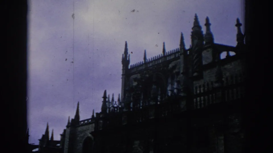1966 Spain 8mm frame showing a silhouetted Gothic cathedral facade and spires in a visitor-shot composition.