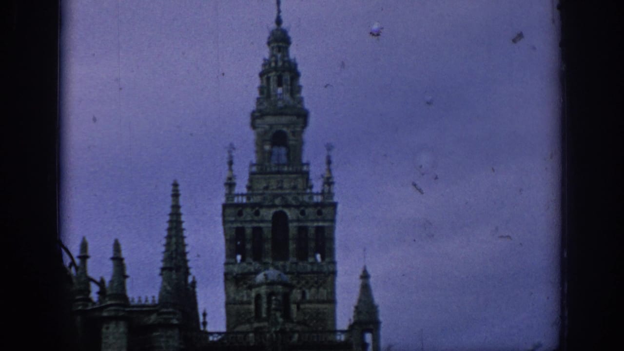 1966 Spain 8mm frame with the Giralda tower rising above Seville Cathedral spires at dusk.