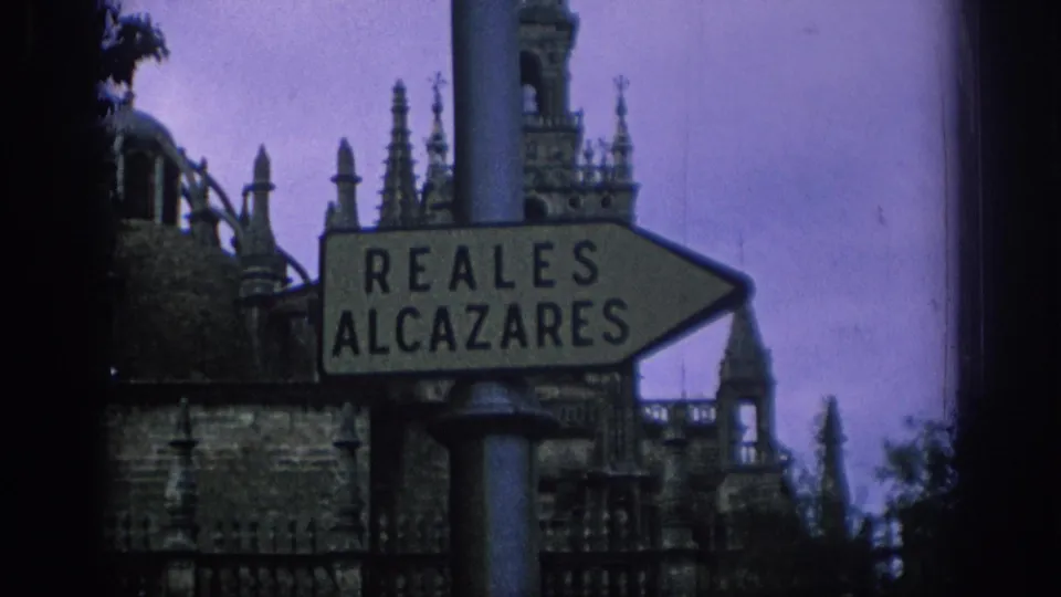 Visitor-shot 1966 Spain frame showing the Reales Alcazares sign before decorative historic architecture and a purple sky.