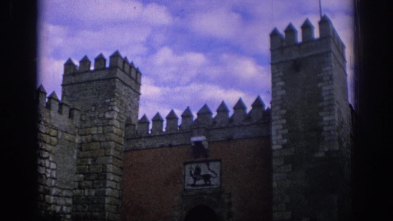 Stone fortress wall with crenellated battlements, square towers, and a heraldic lion panel above a gate.