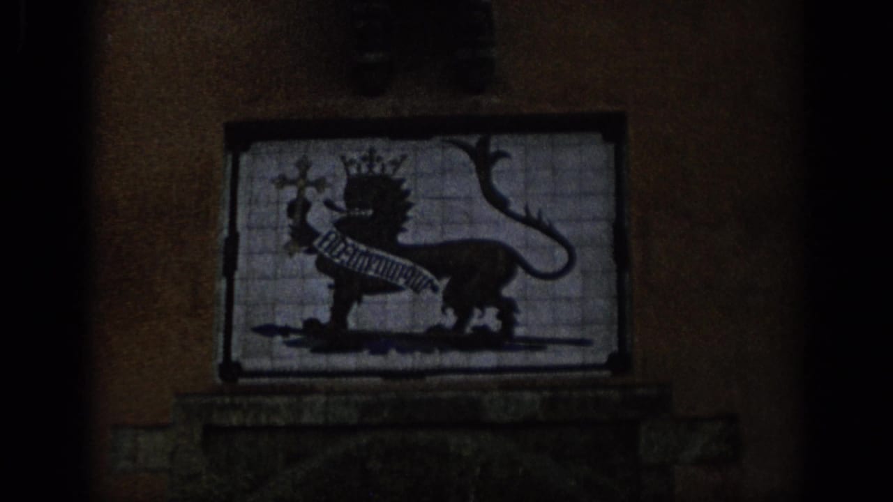 1966 Spain 8mm frame showing a tiled heraldic panel with a crowned lion figure on an exterior wall.