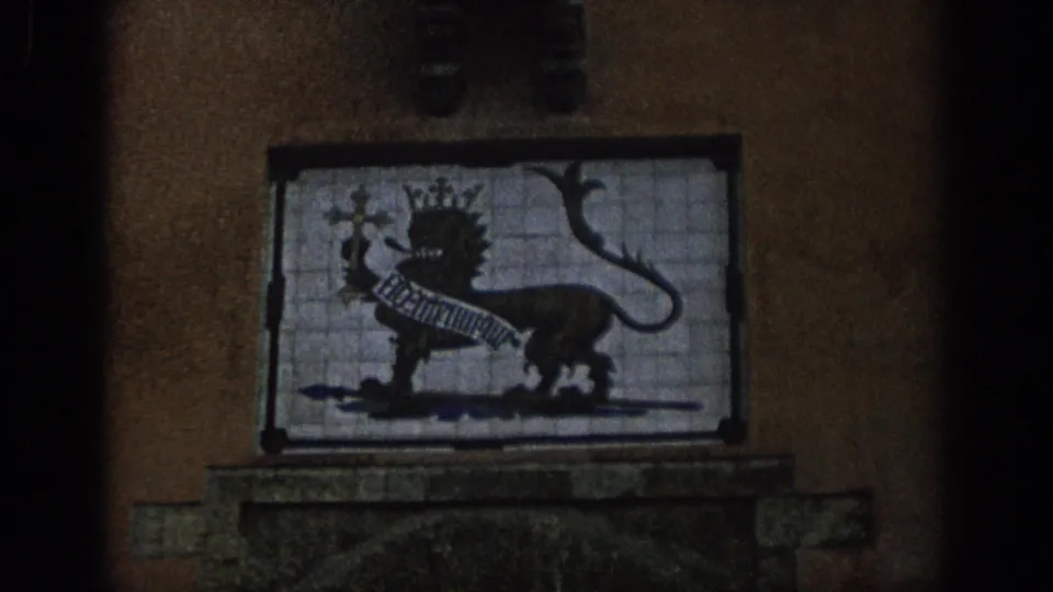 1966 Spain 8mm frame showing a closer view of a crowned lion heraldic tile panel set into a building facade.