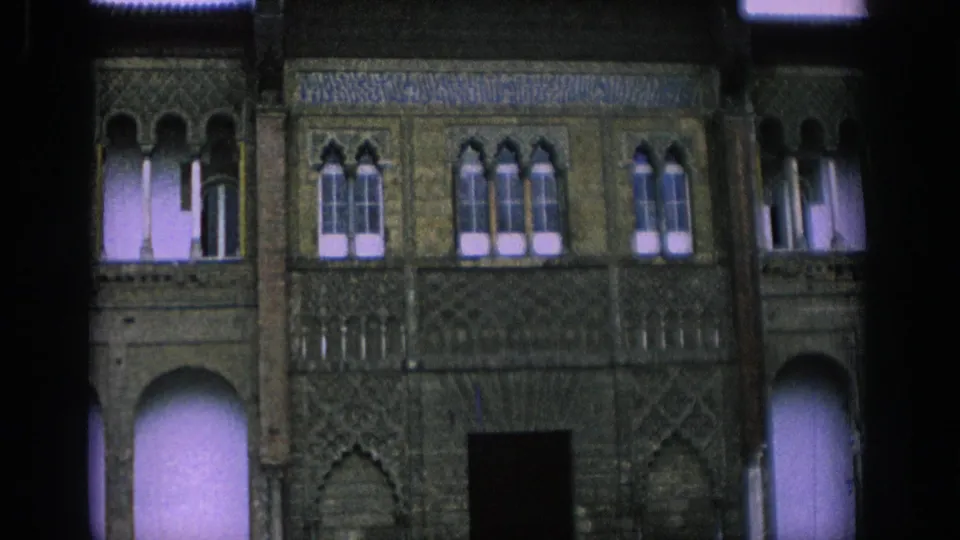 1966 Spain frame showing a decorated historic facade with arched openings, patterned wall panels, windows, and roof tiles.