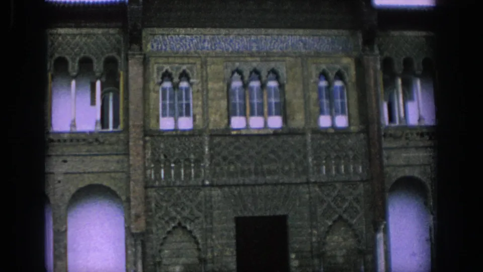 1966 Spain 8mm frame showing a historic Moorish-style facade with arched windows, patterned stonework, and a dark doorway.