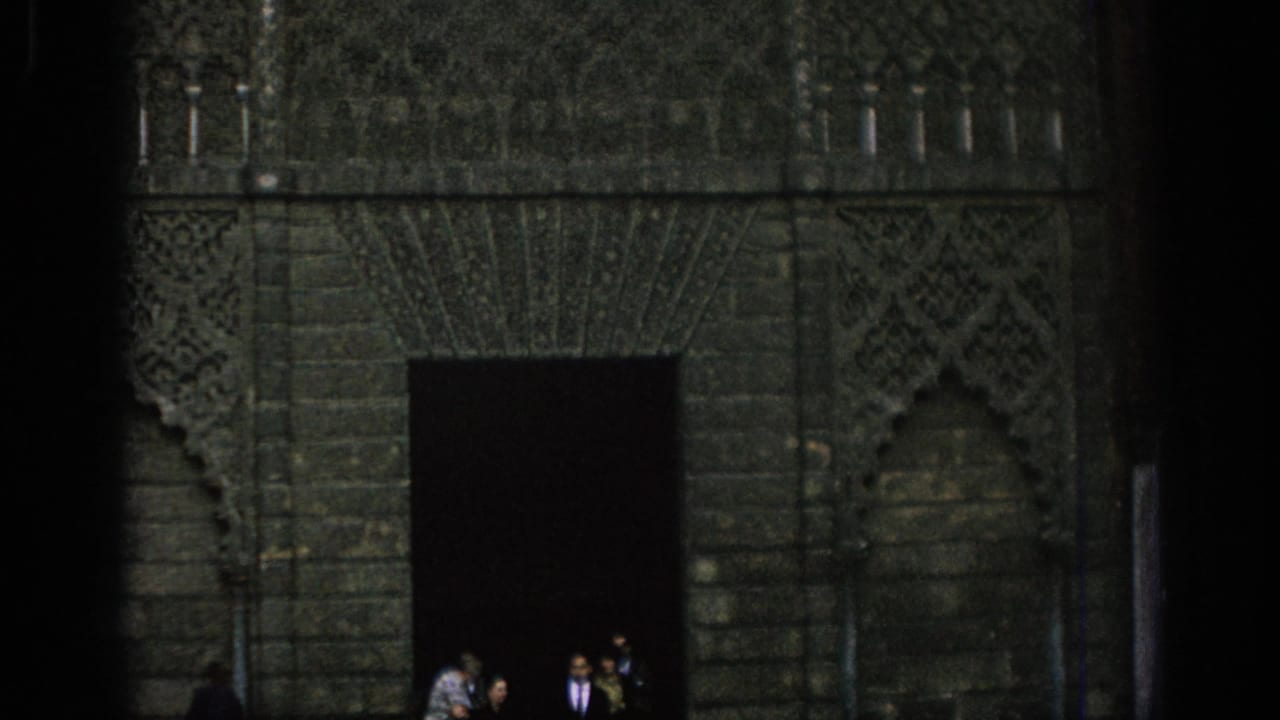 Dark building doorway with patterned stonework and several people near the entrance.