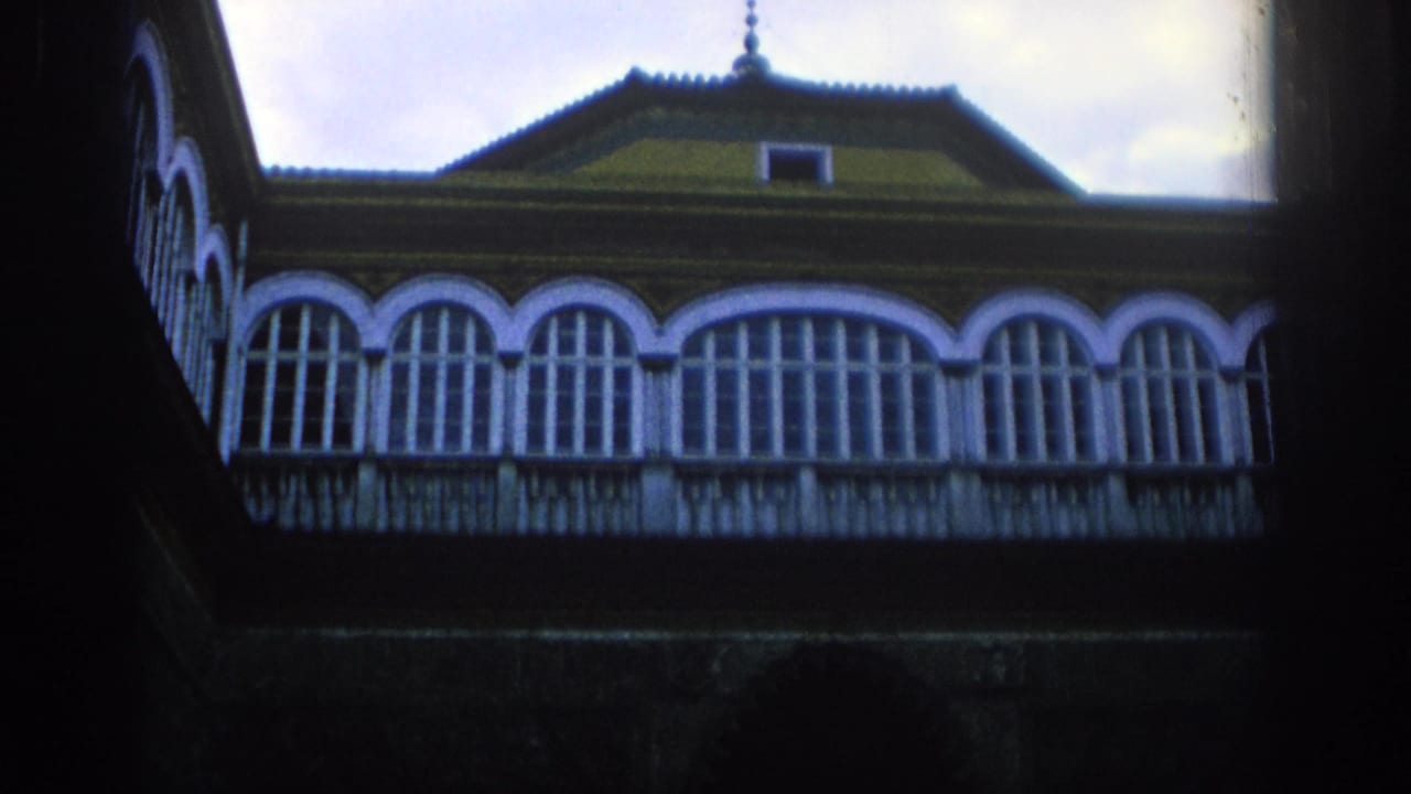 Historic facade with arched windows and balcony rail seen from below.