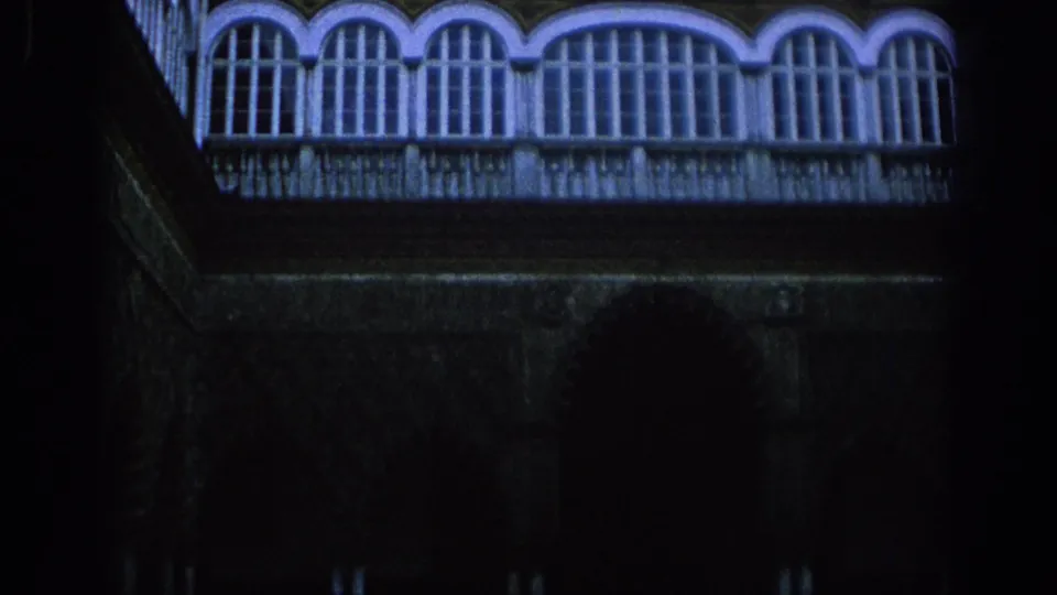 Final 8mm frame from Spain, 1966, showing the ornate balcony windows over a dark wall and arch-shaped opening in deep shadow.