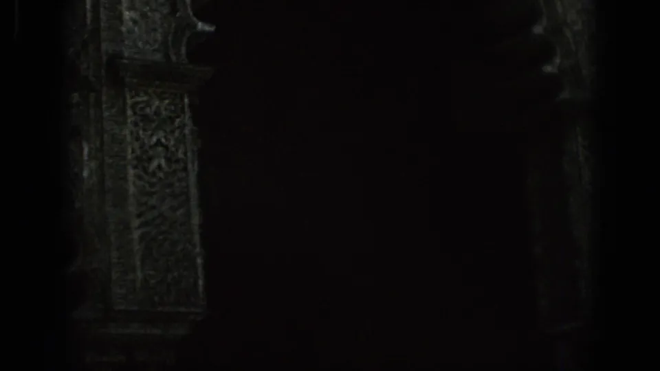 Shadowed 1966 Spain home-movie frame with a figure near a carved archway and heavy night exposure.